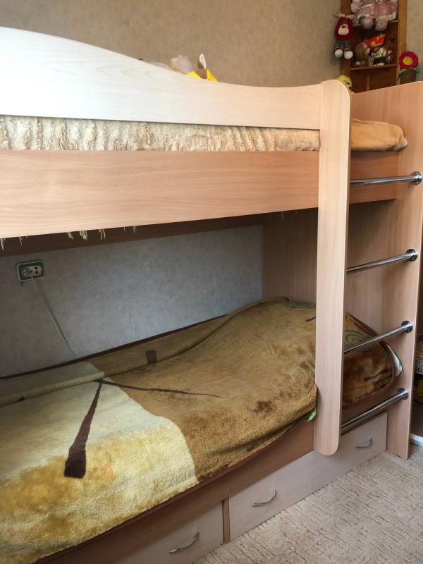 Продается уютная двухъярусная кровать с матрасами, выполненная из ЛДСП в приятном бежевом цвете. - Гай